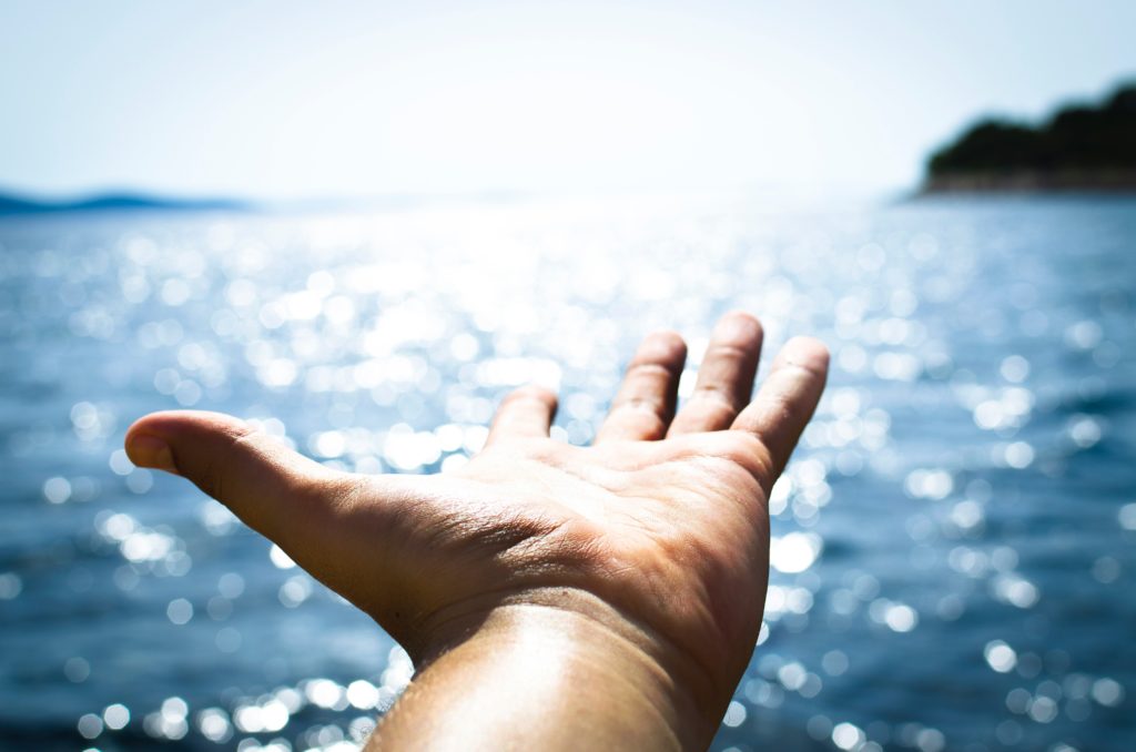 A hand extended towards the sea.